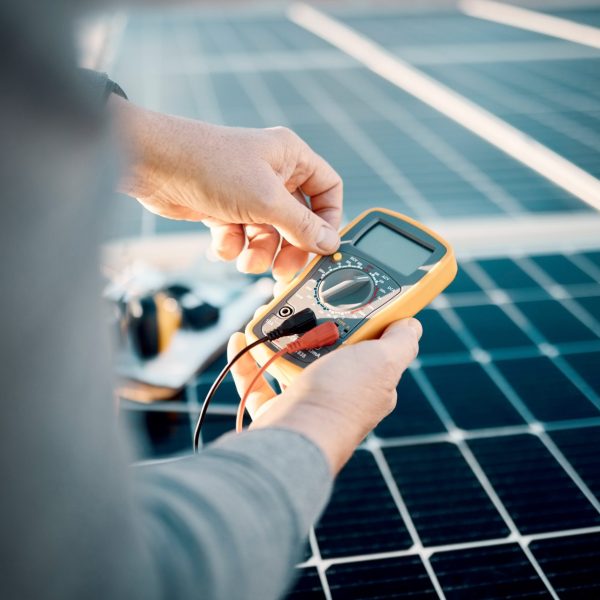 solar-panels-multimeter-and-engineering-hands-scaled